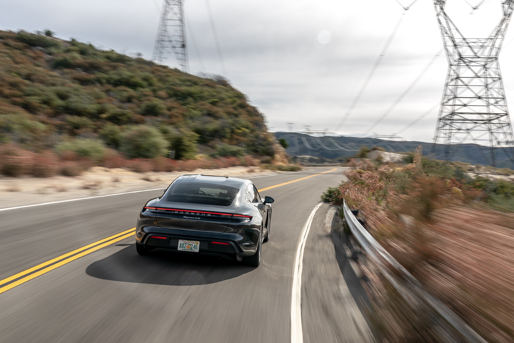 Black Porsche Taycan driving rear